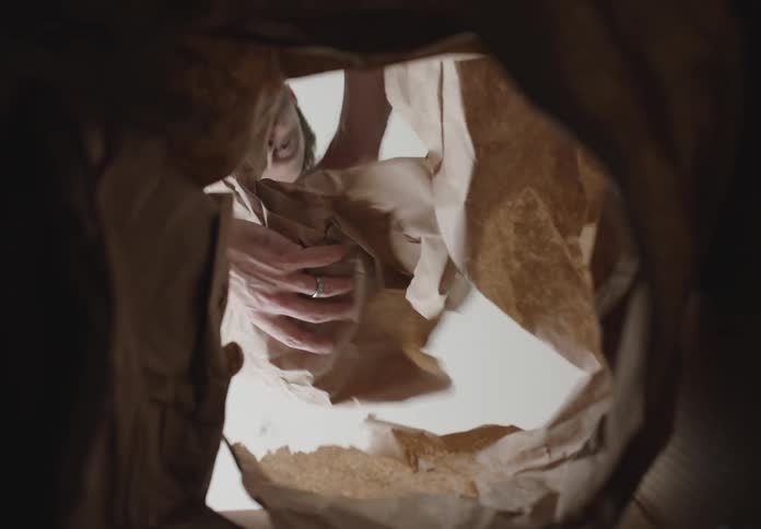 A man picking up a box of food from a paper bag
