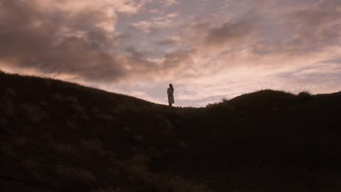 A woman stands up on the hill at sunrise