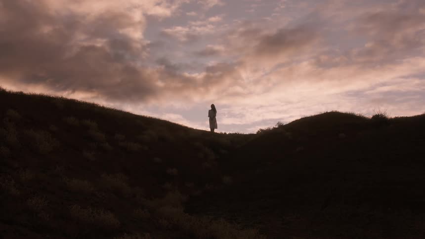 A woman stands up on the hill at sunrise