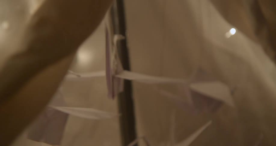 Person inspecting a hanging piece of origami