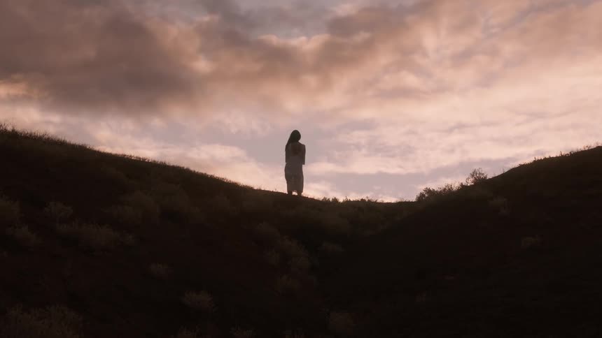 A woman walks over the hill at sunrise