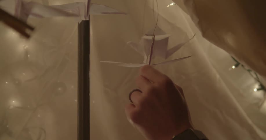 Origami birds hang from the inside of a blanket tent