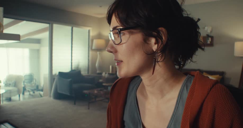 A woman intently analyzes data charts on a computer monitor in a cozy home office