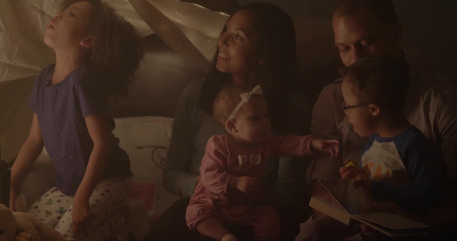 A family sits together under a blanket tent