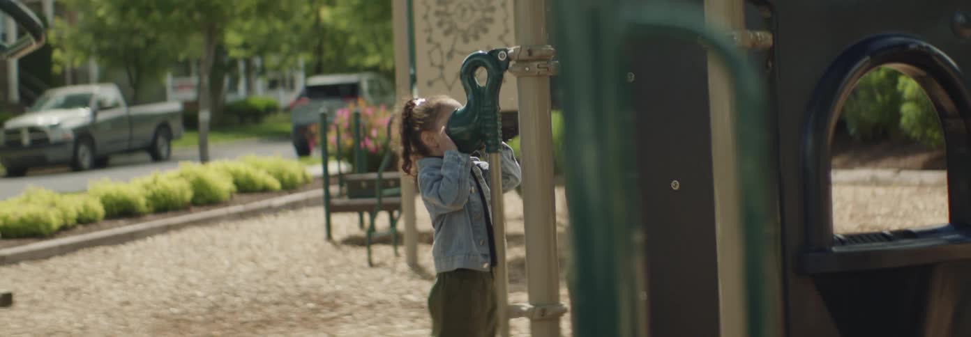 A young girl plays on a playground structure in a quiet suburban neighborhood