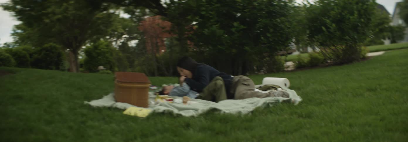 Mother and daughter hold hands while lying down during an outdoor picnic in daytime