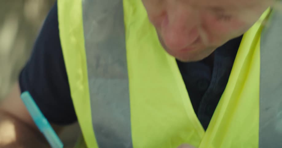 A man is writing on sticky notes as he looks at a blueprint