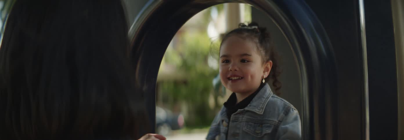 A mother and daughter share a joyful close moment on a playground as the little girl talks excitedly