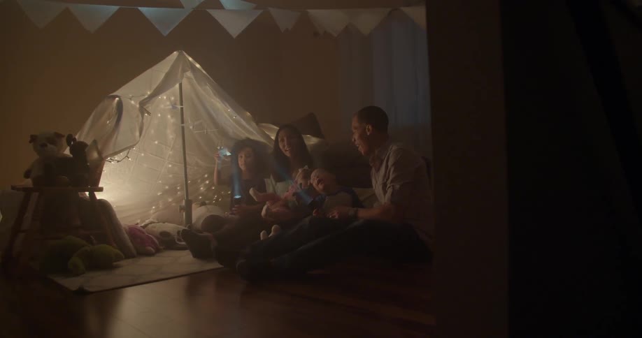 Group of people including children shining flashlights indoors at some papers hanging from some lines