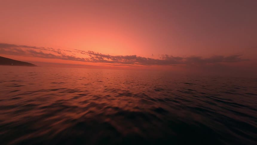 Aerial flight over the beach and the ocean at sunset