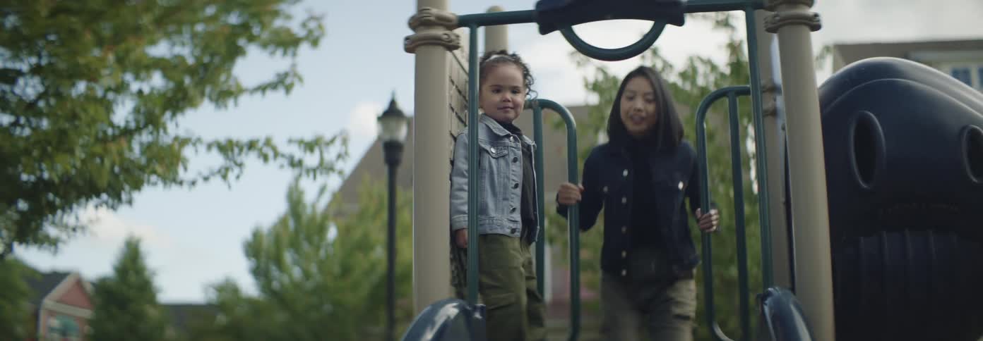 Mother and daughter joyfully slide down together at a park playground