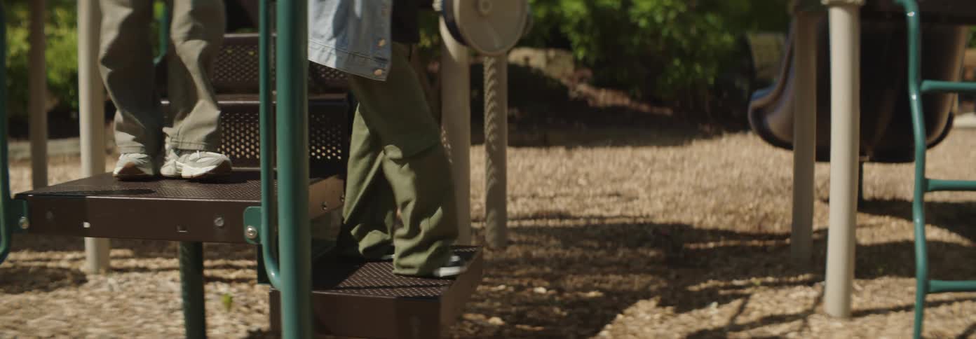 A child and a woman going down a slide at a playground