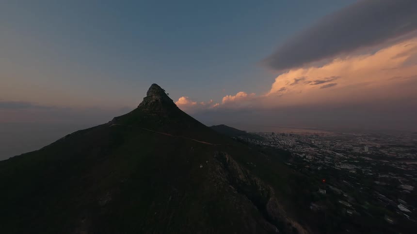 A dormant volcano surrounded by nature sits under a sunrise