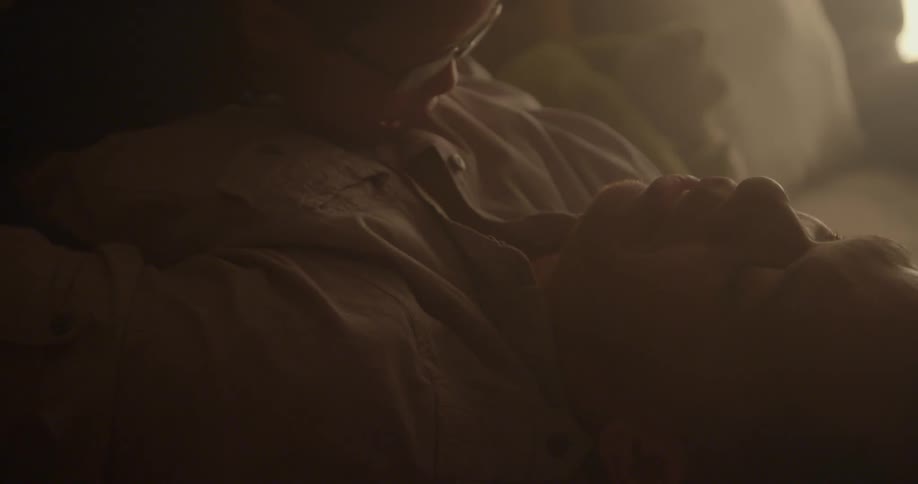Man lying on his back indoors with a young child bobbing on his chest and then caressing him