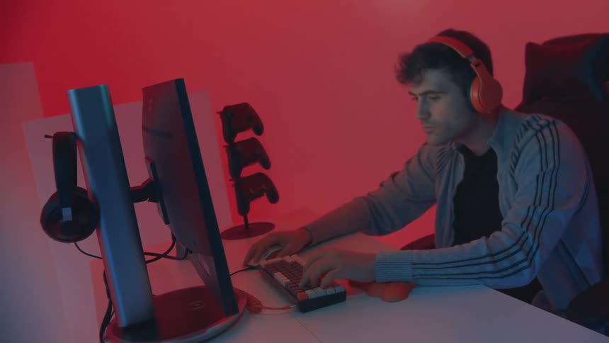 A man playing video game on a computer with headset on in a room