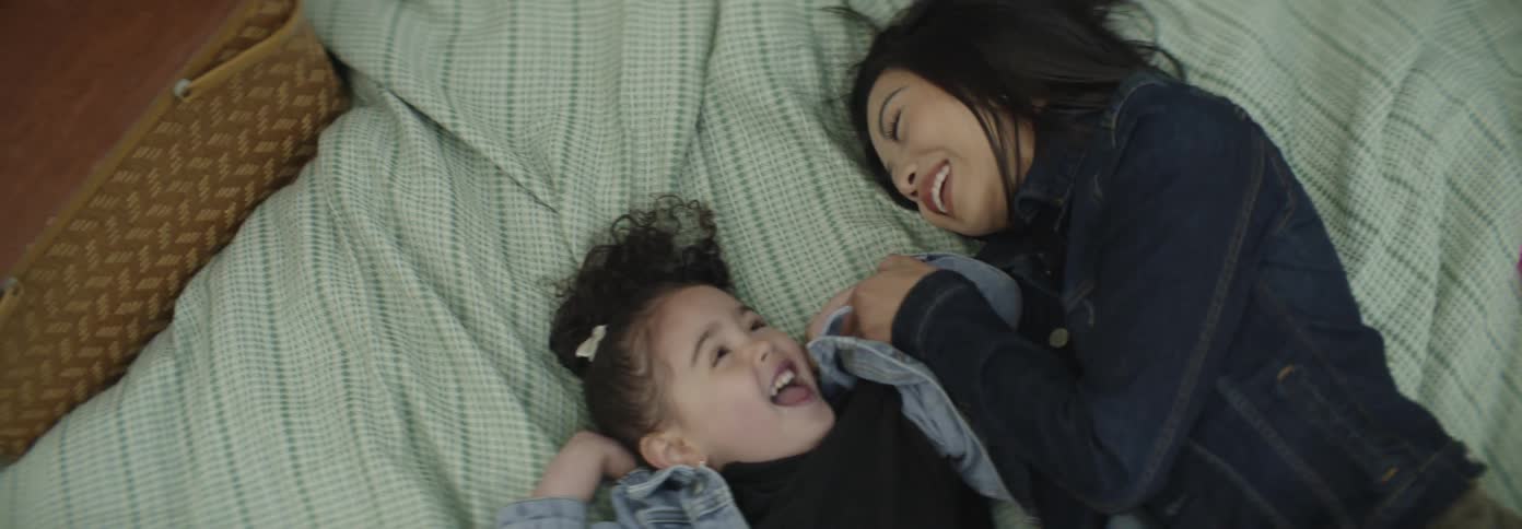 A mother and daughter lay on a blanket outside