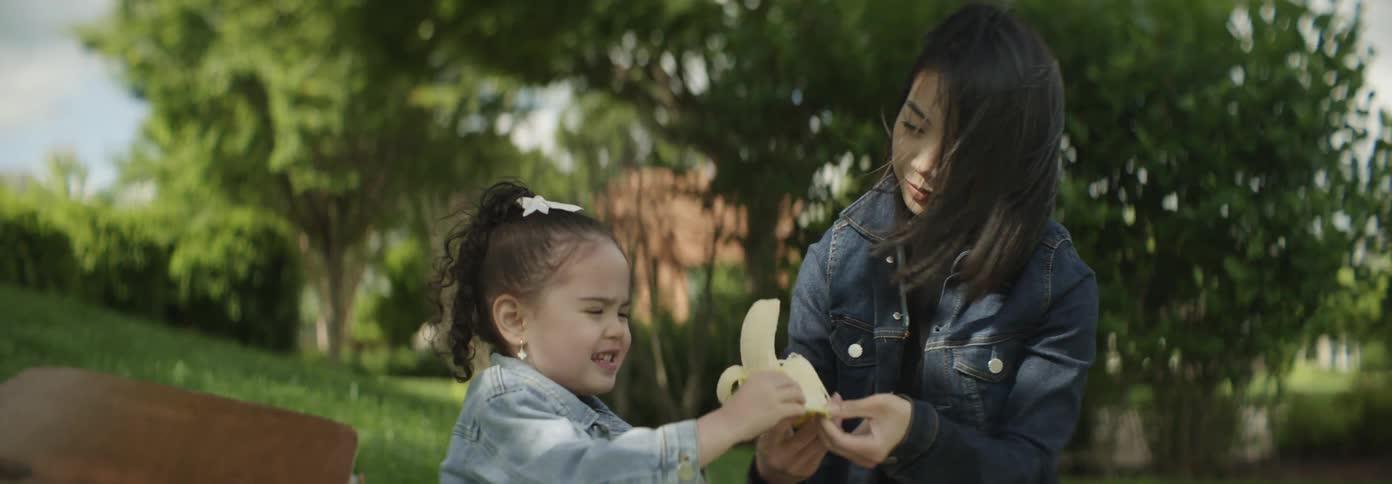 A mother gives her daughter a banana at a picnic