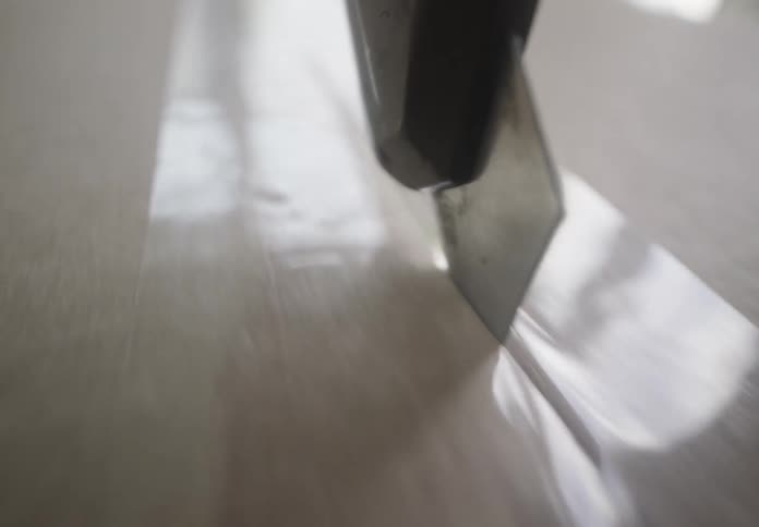 Point of view cutting packaging tape with sharp blade across a box