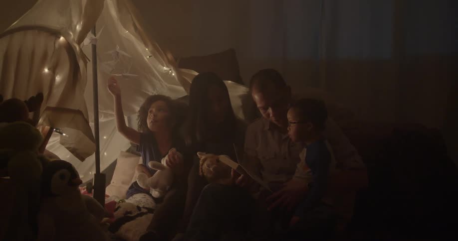 A family sits under a tent in a dark room