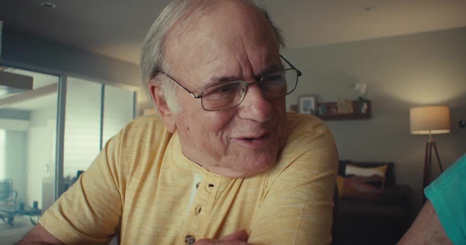 An elderly couple looks at a laptop and takes notes while having a conversation