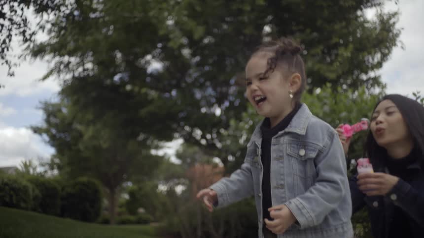 A woman and a child playing with soap bubbles outdoors