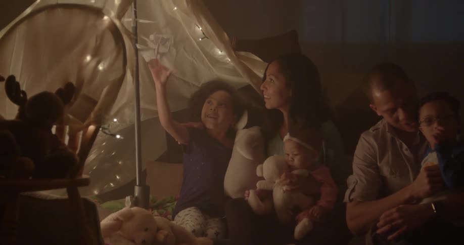 A family sits on the floor under a blanket tent