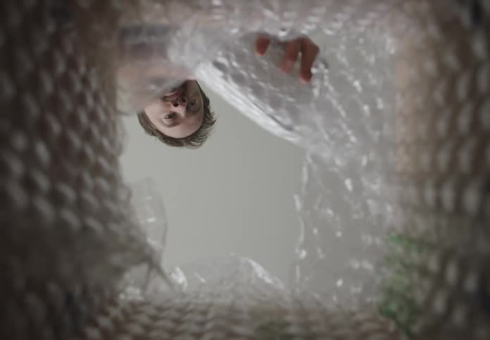 Point of vew man wrapping small box with bubble wrap placing in large box and closing lid