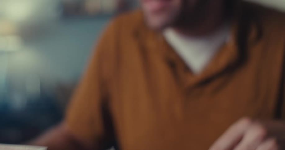 Close up of a man carefully stacking playing cards in a triangular pattern in a room