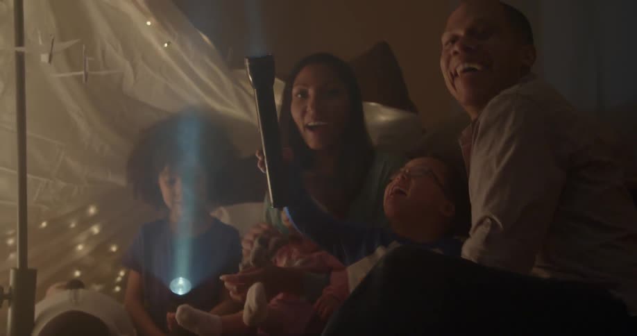 Parents and children playing with flashlights in home at night