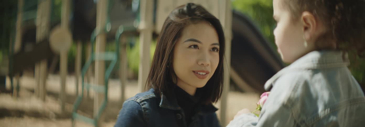 A young woman is listening to a girl holding a pink flower