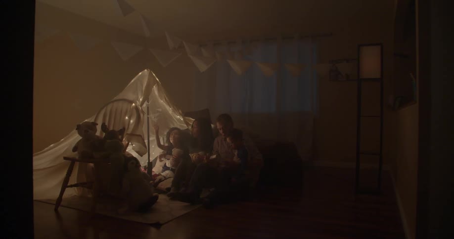 A family is sitting under a small tent