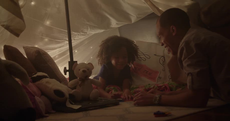 A man plays with a girl in a dark room
