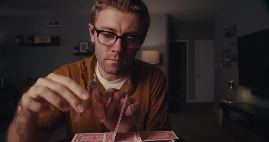 Timelapse of a man building a card pyramid indoors