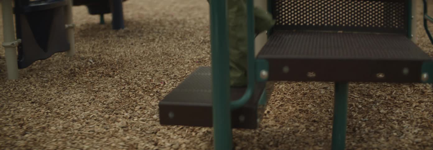 Girl climbs down the stairs of the equipment in a playground during the daytime