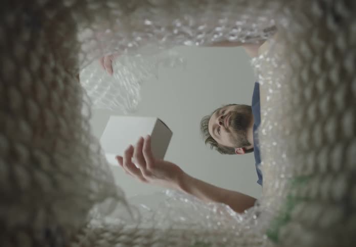 The man removes the bubble wrap from his package