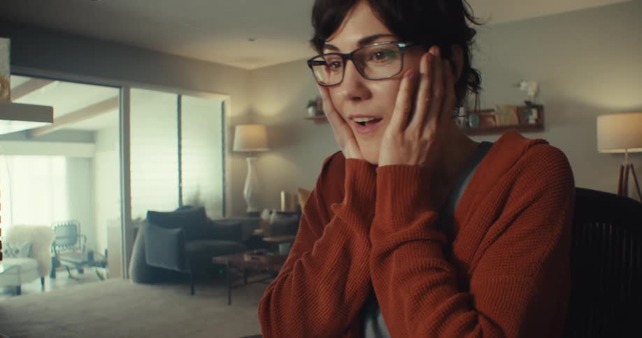 A woman reacts with happy surprise while looking at stock data on her computer screen