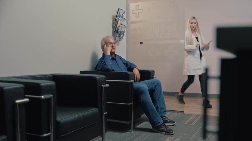 A doctor speaks with an older man seated in a medical waiting room