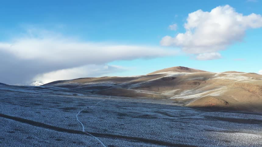 River winds across an icy plain near the mountains on a cloudy winter day