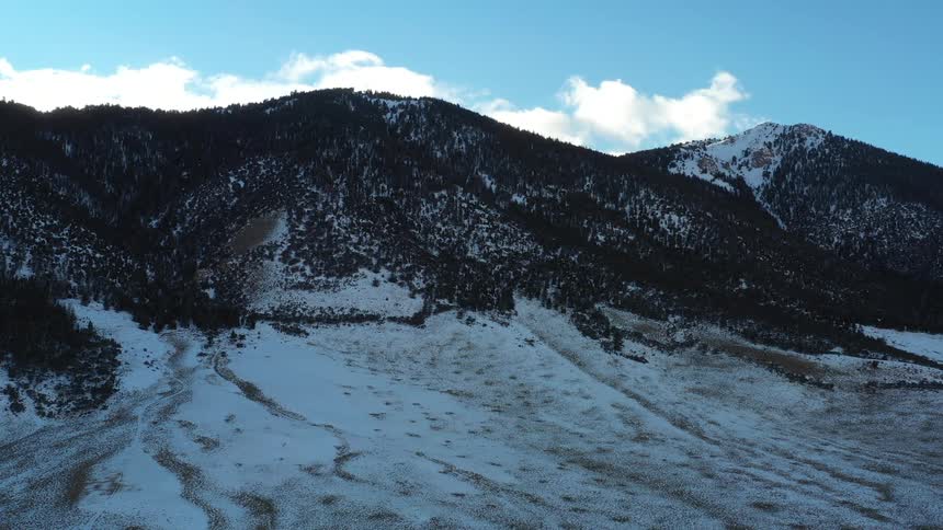 A mountain range is shown with a bight blue sky above