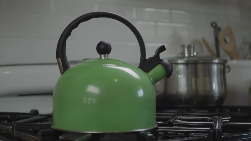 A tea kettle steams on a stove