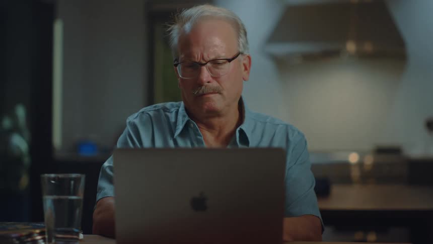An older man using his laptop at a table