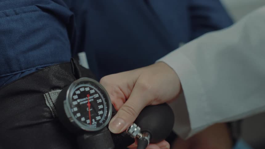 A healthcare professional is checking a patients blood pressure using a manual sphygmomanometer