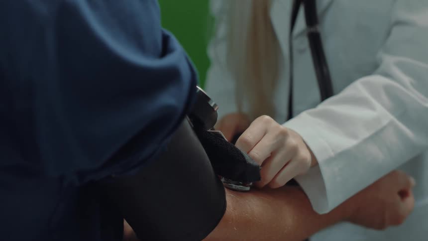 A doctor is taking a patients blood pressure in a medical office