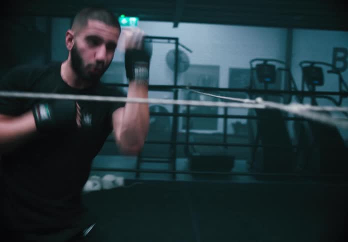 A man is shadowboxing inside a dimly lit gym