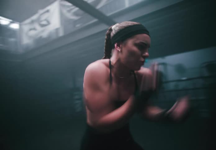 Female boxer trains in the boxing ring of a boxing gym