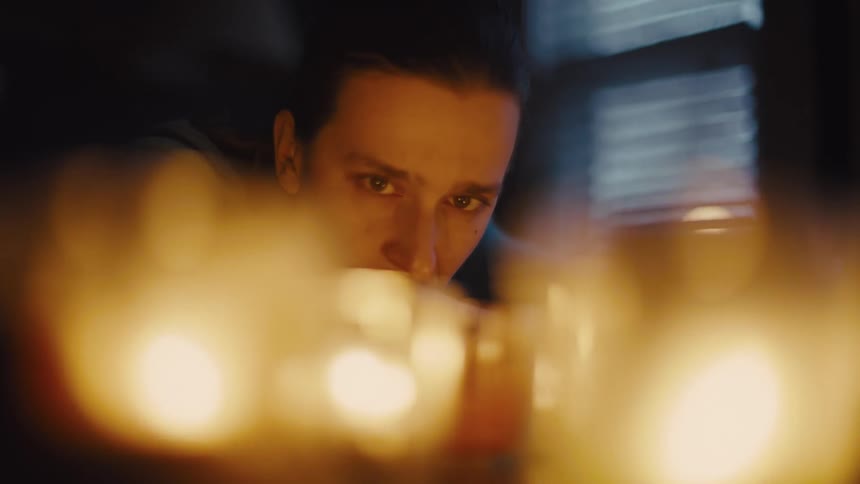 A person stares intently at a group of glowing candles lost in deep thought