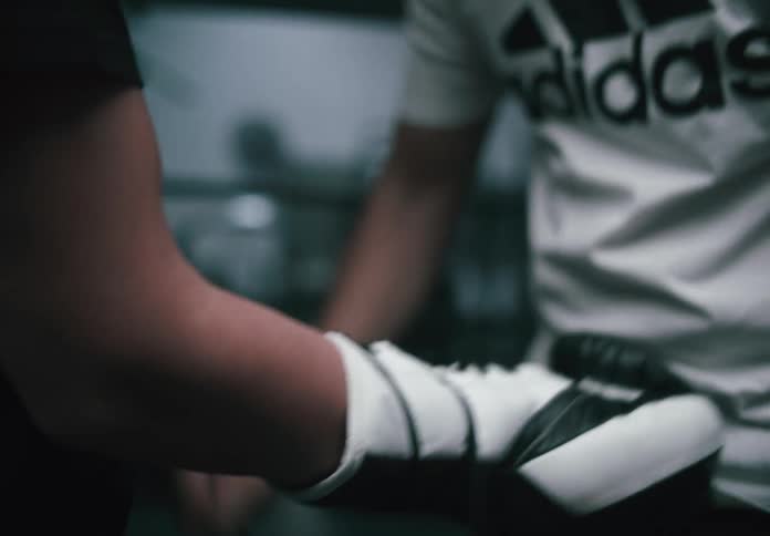 A person is tightly wrapping another persons ankle likely for athletic support