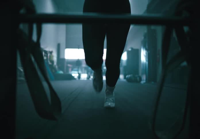 A woman runs in the gym while pushing a weighted sled