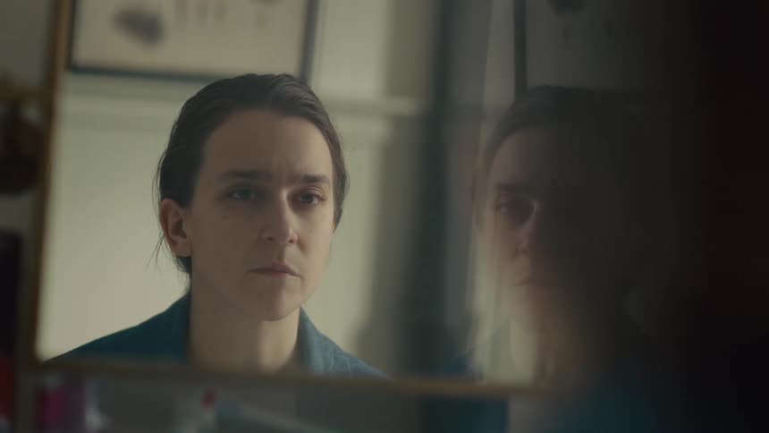 A sad woman looks at the mirror without confidence