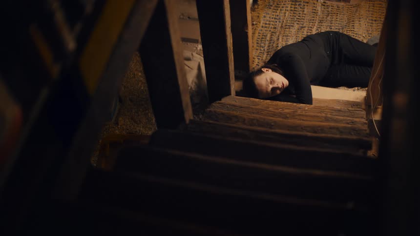 A woman lies down at the bottom of the staircase